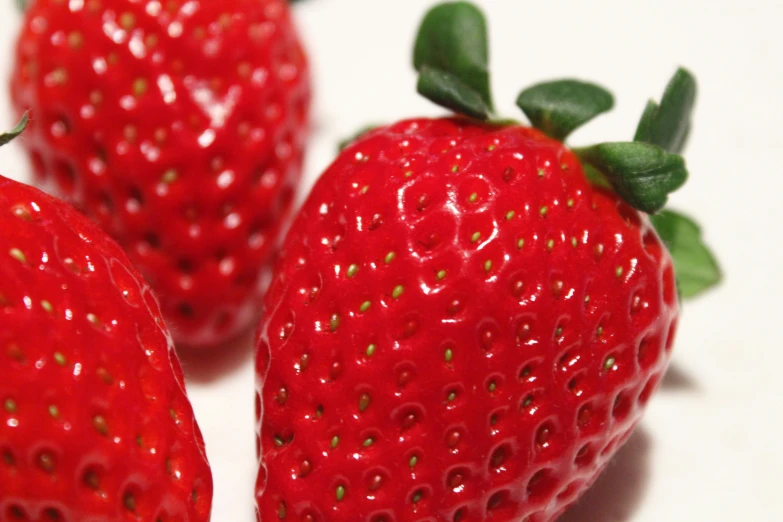 three red strawberries are shown sitting on the table