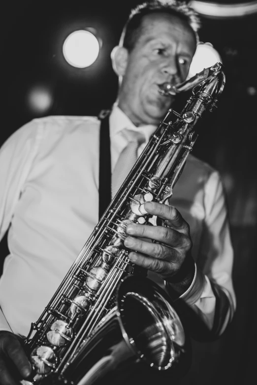 a man playing a saxophone while standing with his head turned to the right