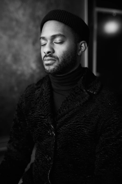 a man with his eyes closed standing in front of a wall