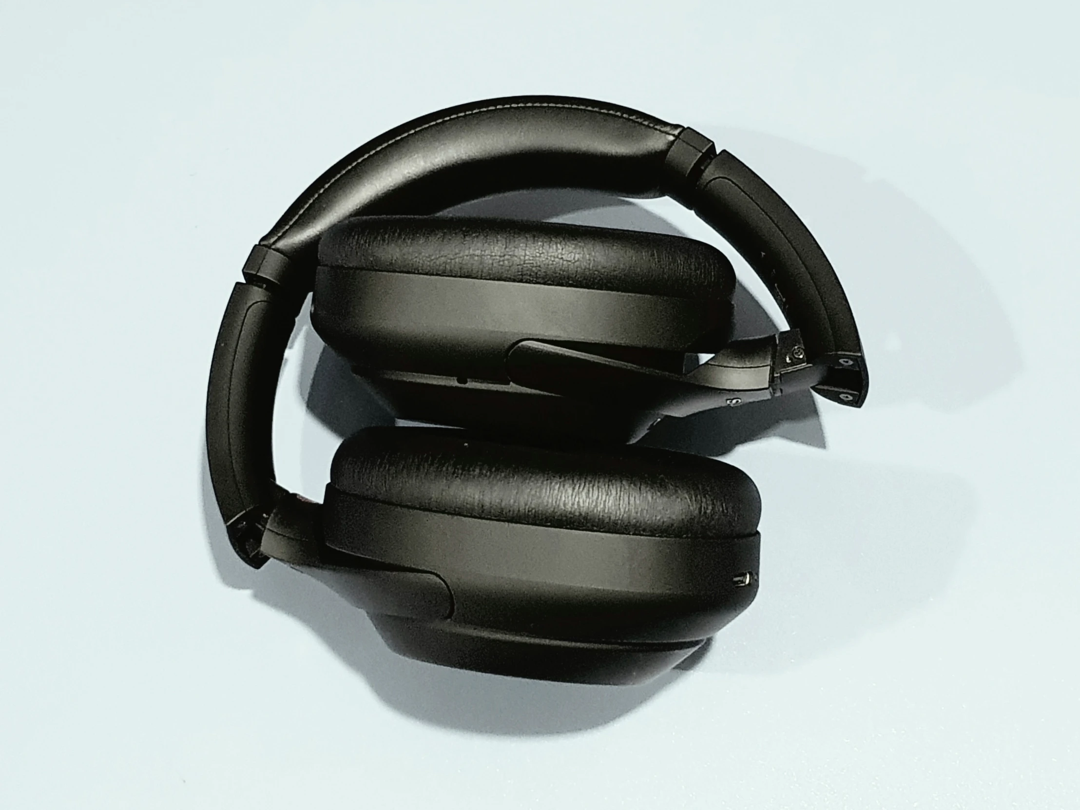 two pairs of black headphones lie on a white surface