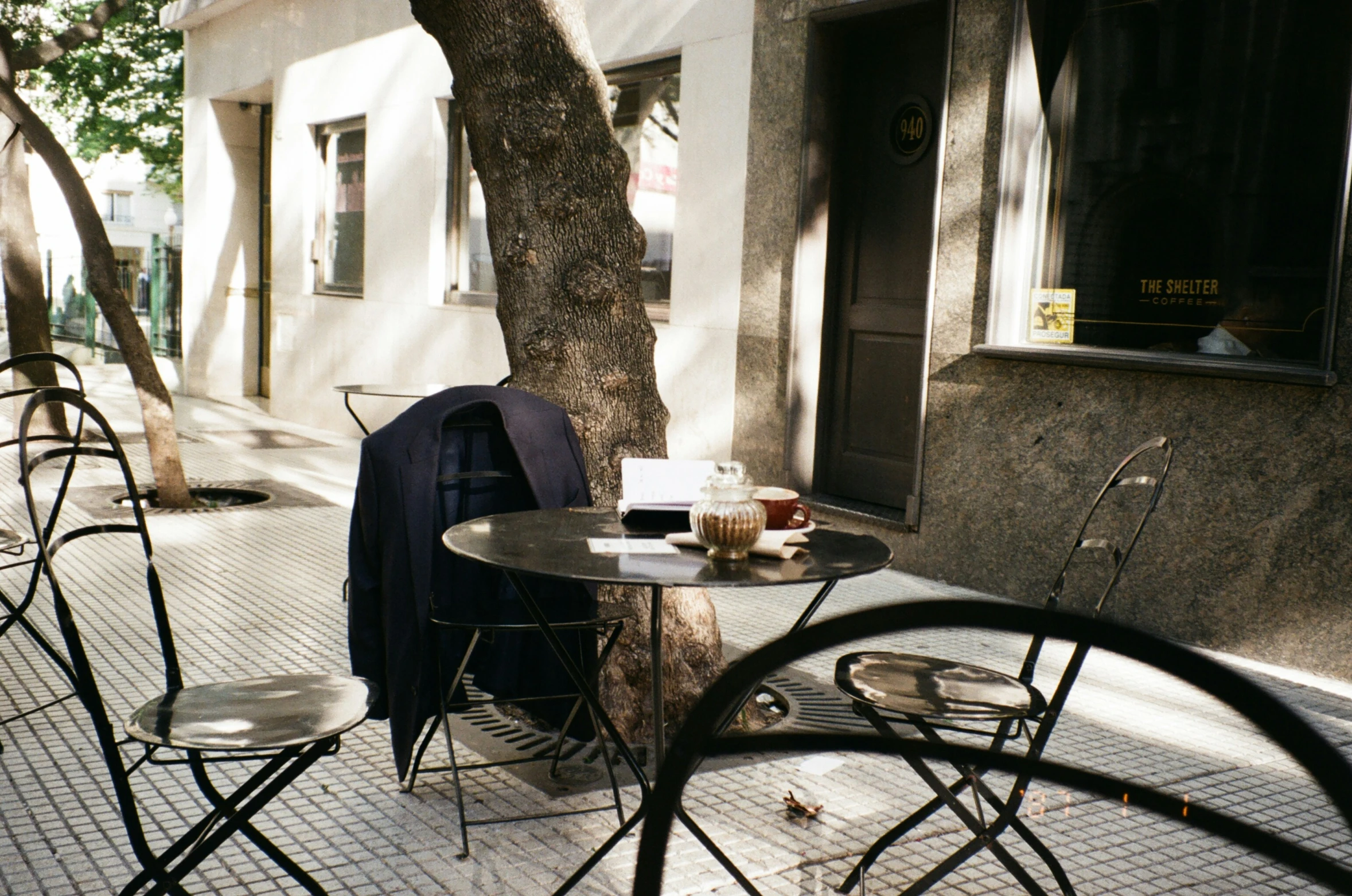 a white building some chairs a table and a tree