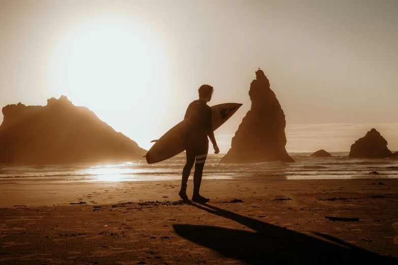 a man on the beach holding a surfboard