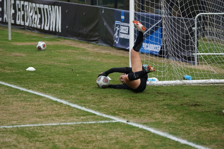 a soccer goalie has fallen to the ground in pain