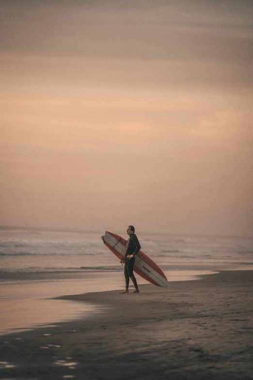 a man carrying a surfboard on a sandy beach