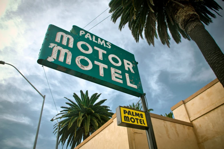 a palm tree stands next to the palm motel sign