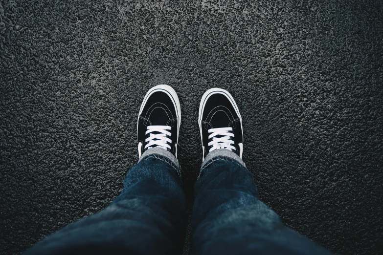 a person's feet wearing blue jeans and white sneakers