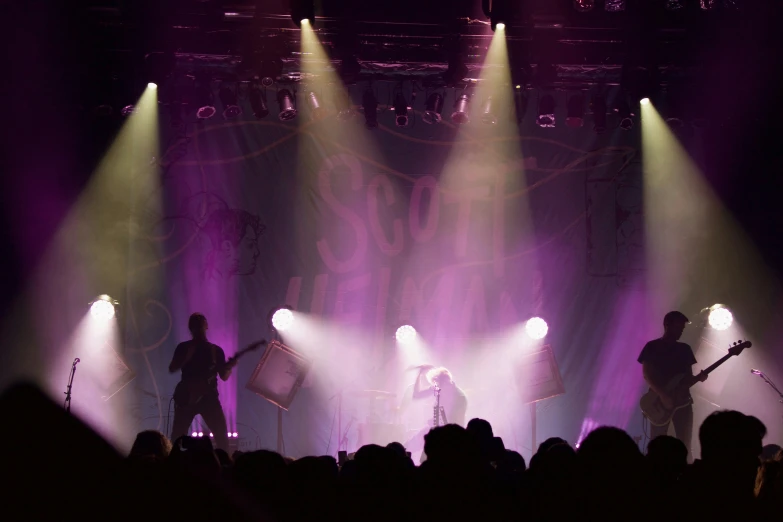 three musicians on stage with spotlights in the background