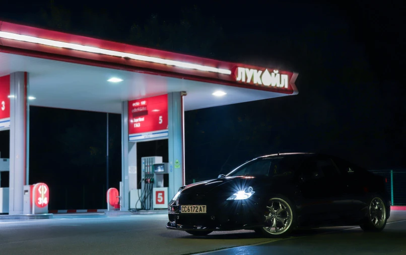 a black car sits in front of a gas station at night