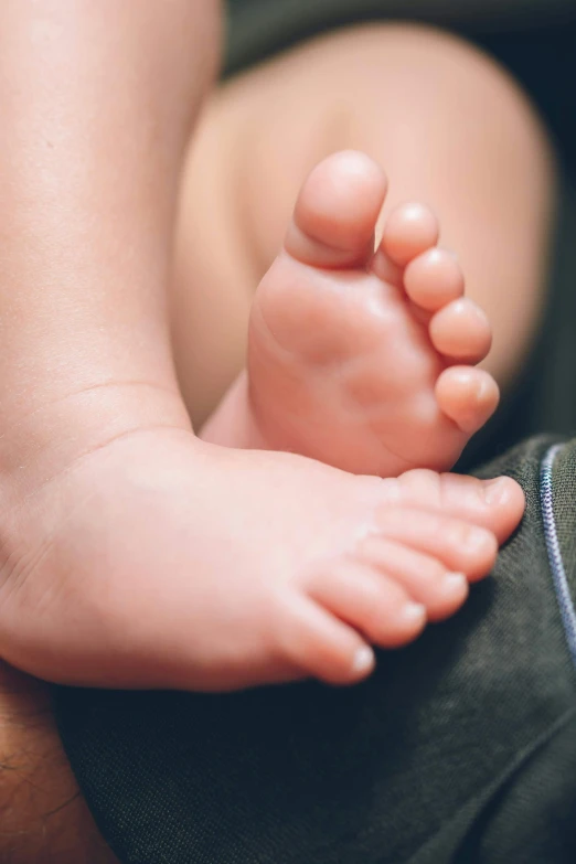 the infant's foot is being held in the parent's lap