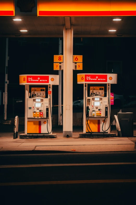 two white and yellow gas pumps next to each other on the side of a road