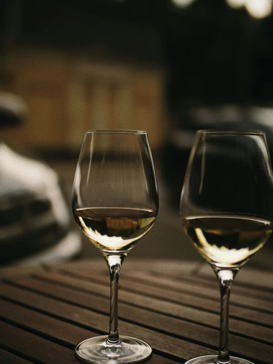 two glasses of white wine sitting on a table