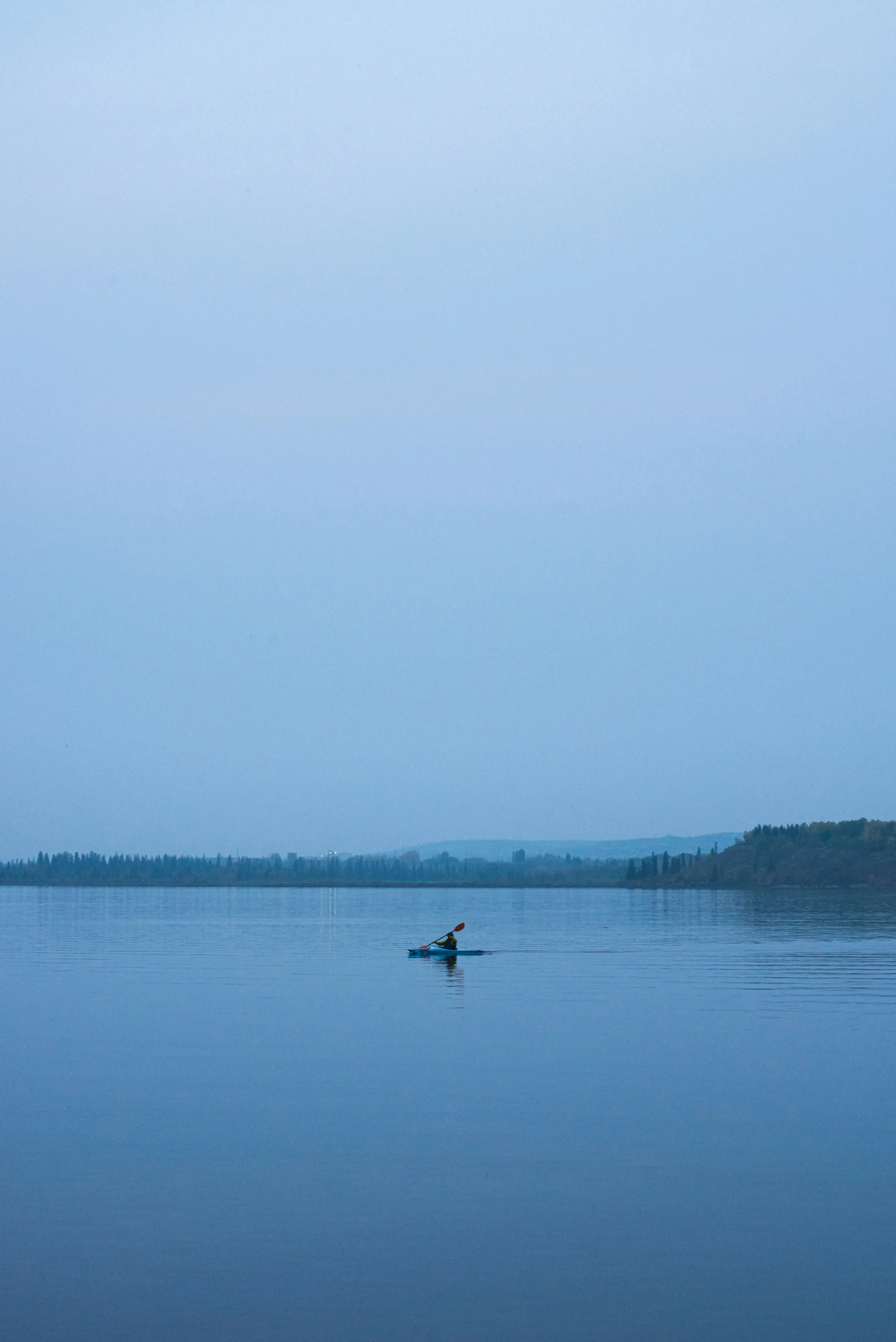 a lone boat floats in a calm blue lake