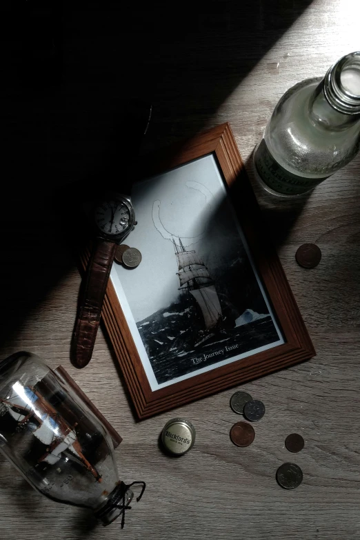 a picture frame next to an old fashioned glass container with some coins scattered around it