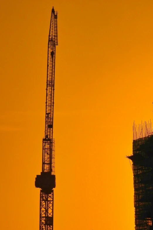 the very tall crane is next to a building under construction