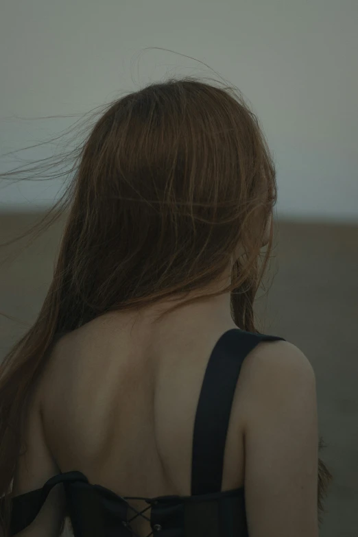 a woman with long hair and backless top standing in the desert