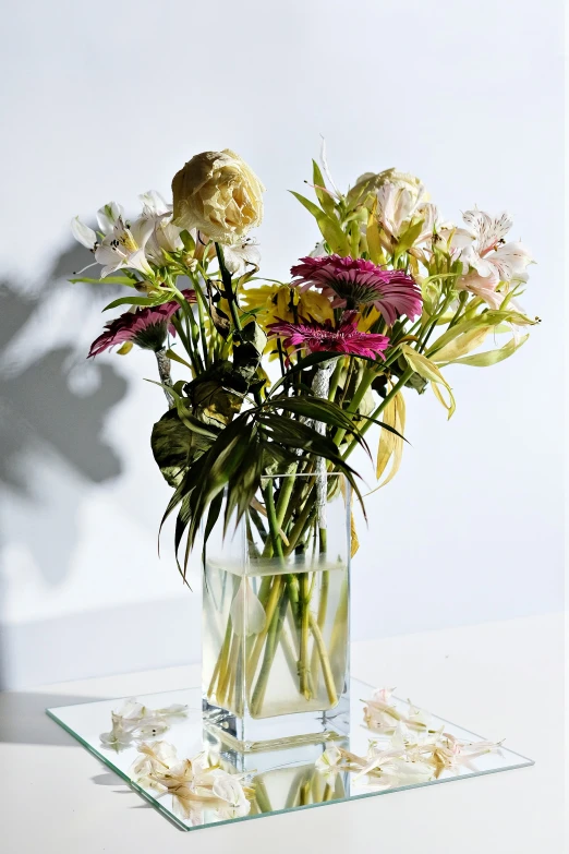 some flowers in a vase and some shells on a table