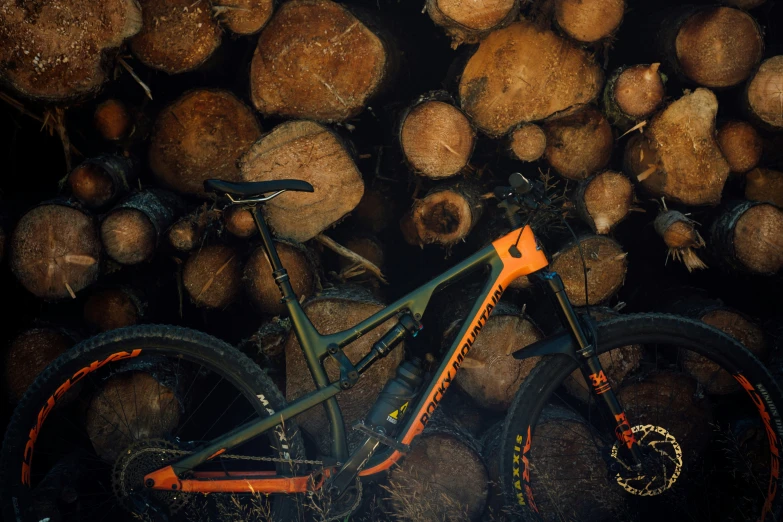 an orange and black bike sitting in a pile of wood