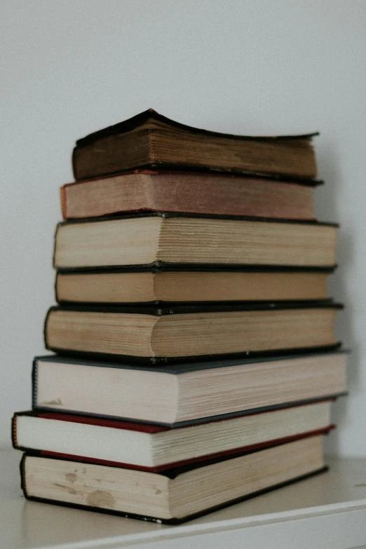 stack of books sitting on top of a white bookcase