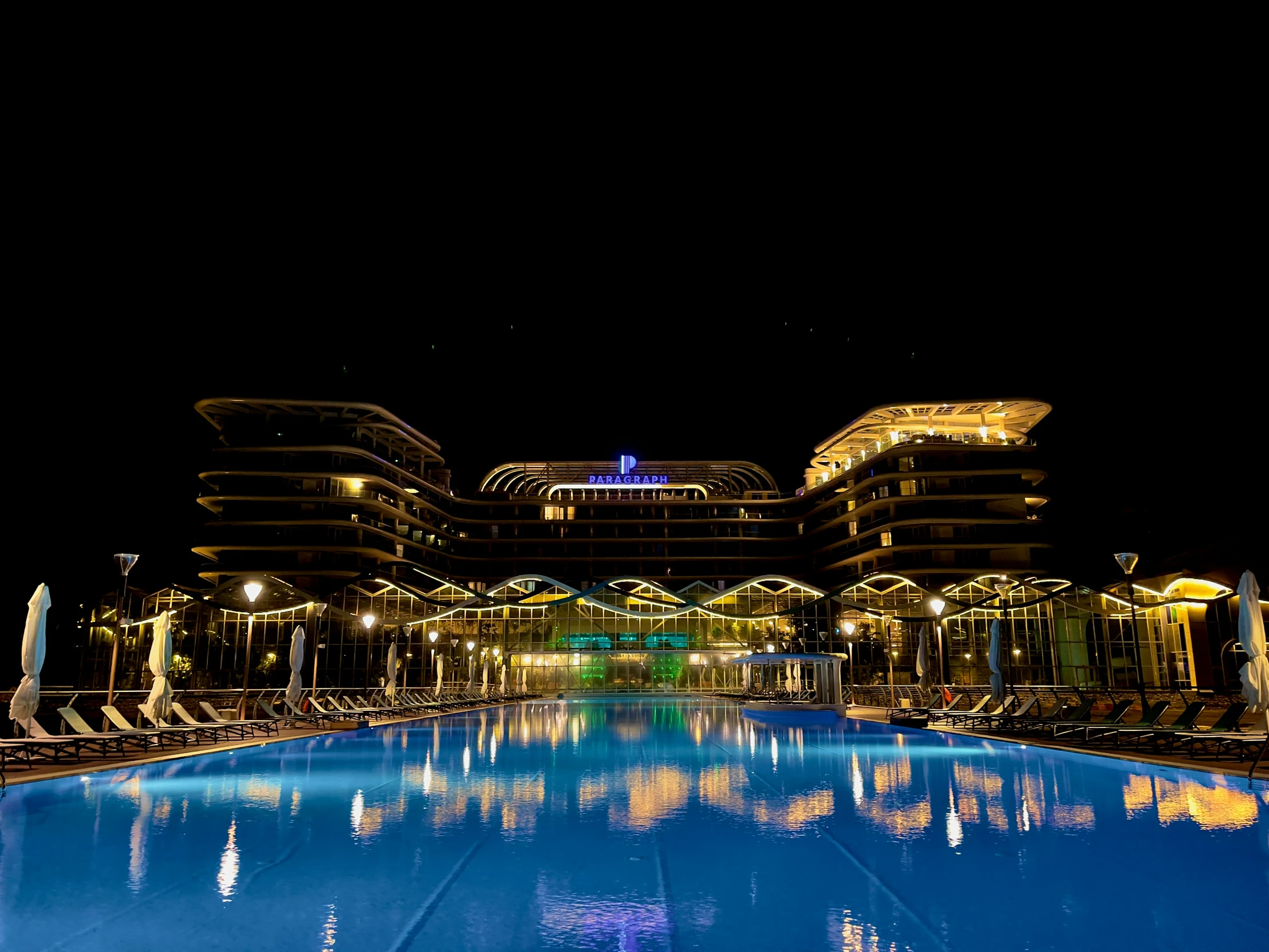 an outdoor pool at night next to some buildings