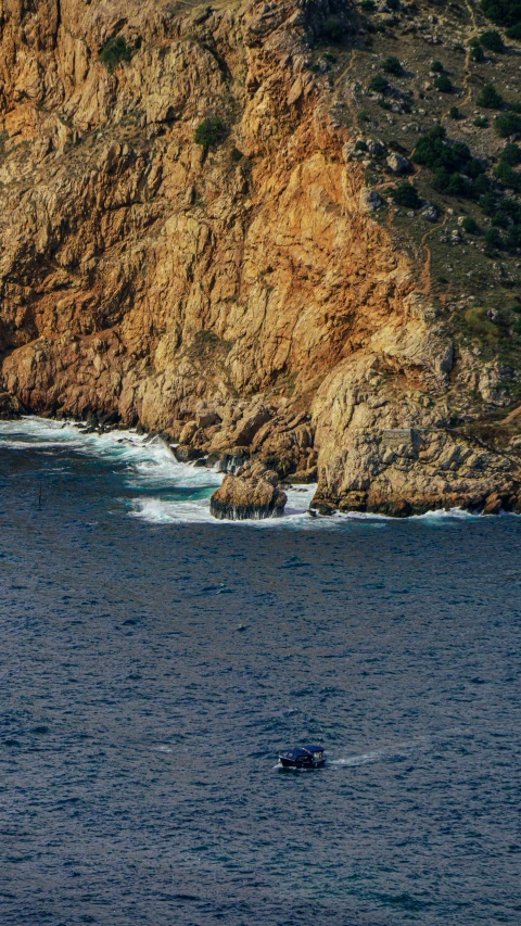 two boats are out in the water by some big cliffs