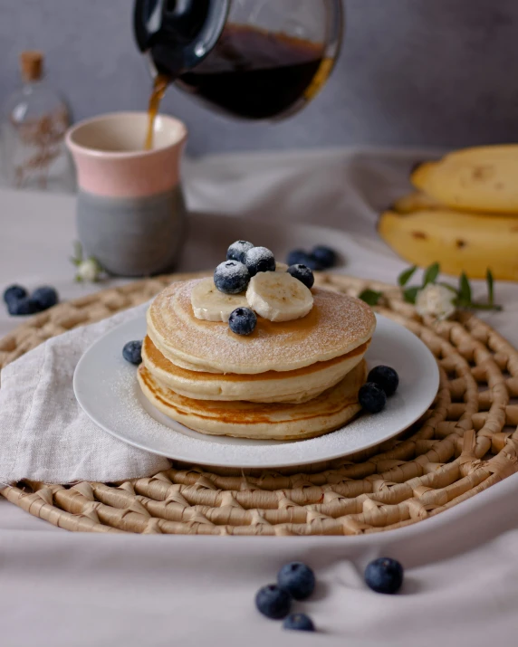 a plate of pancakes with blueberries and syrup