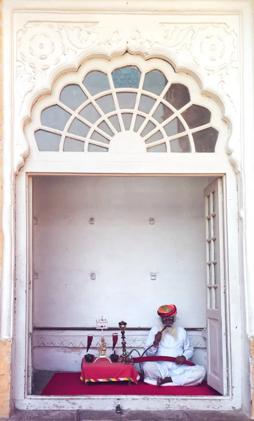 a person sitting inside of a white building with a small window on it