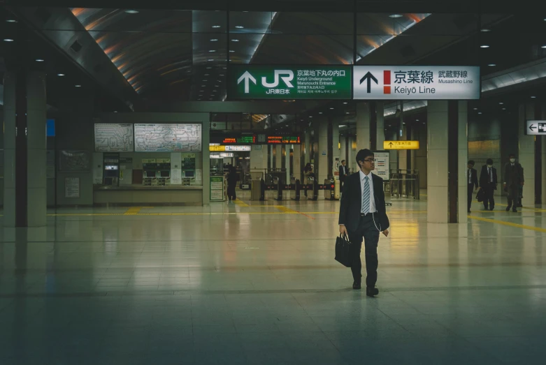 a man walking through an airport wearing a business suit