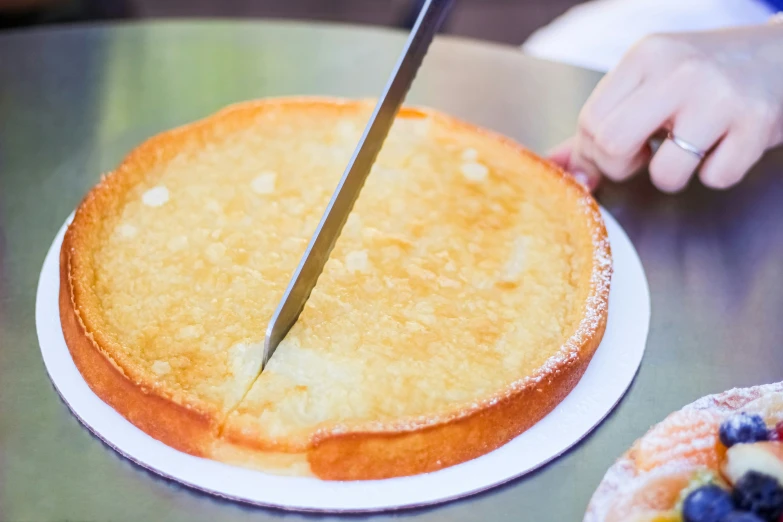 a person slicing into a cake on a table