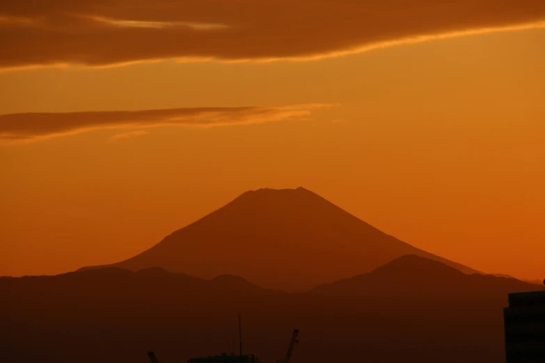 a silhouette of a mountainside with a building in the foreground