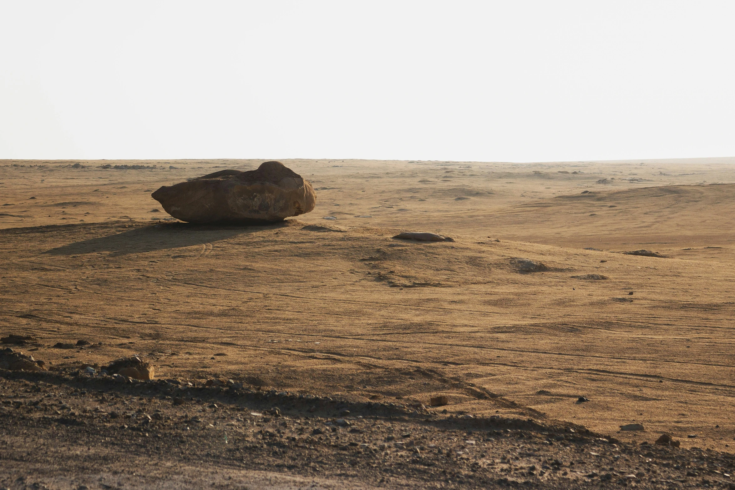 a large rock sitting on top of a dry grass field