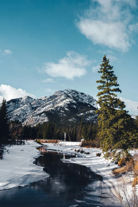 a mountain range and river with snow on the ground