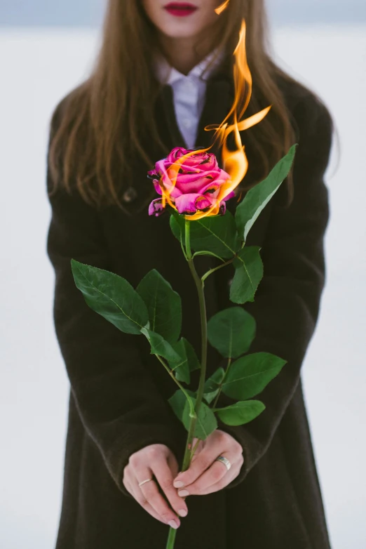 the woman is holding a flower that has flames coming from it