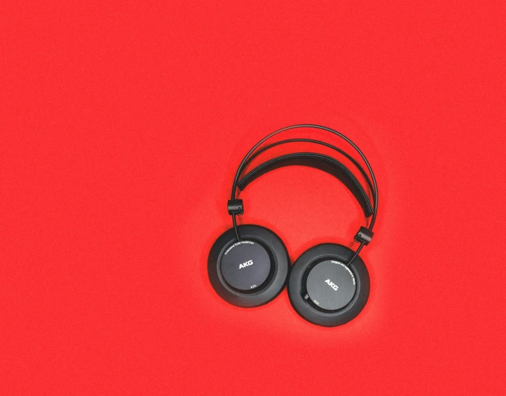 a pair of headphones sits against a bright red backdrop