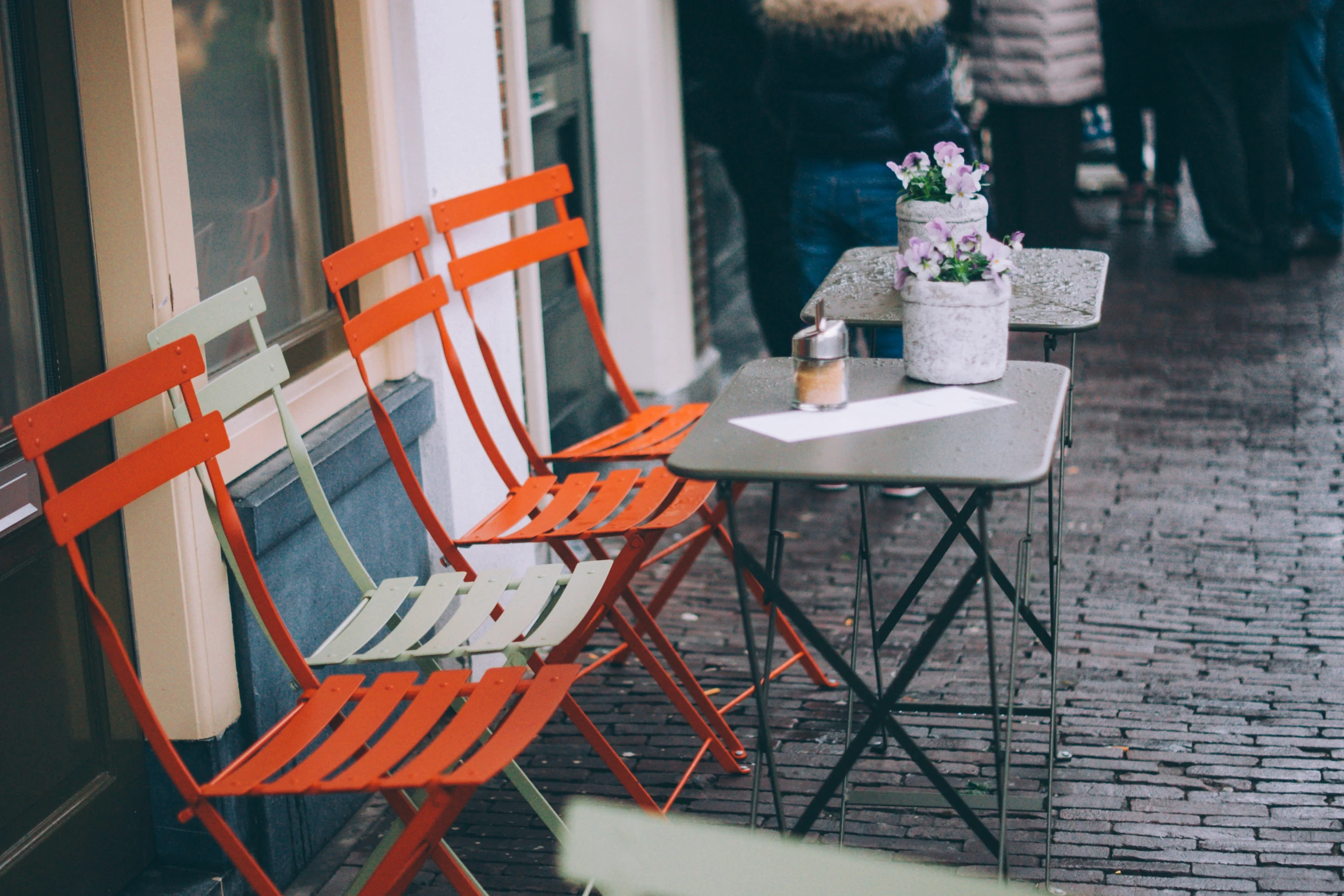 three folding chairs and two tables sitting outside of a cafe