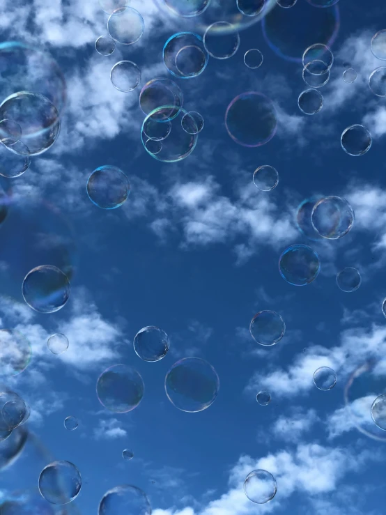 several soap bubbles floating in the sky against a cloudy blue background