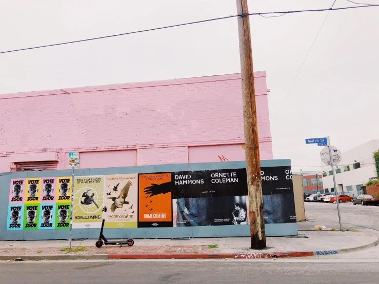 a pink building is surrounded by posters that have been displayed on the side of it