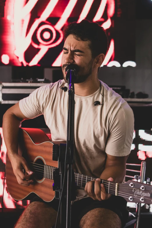 a man is playing a guitar while sitting in front of a microphone