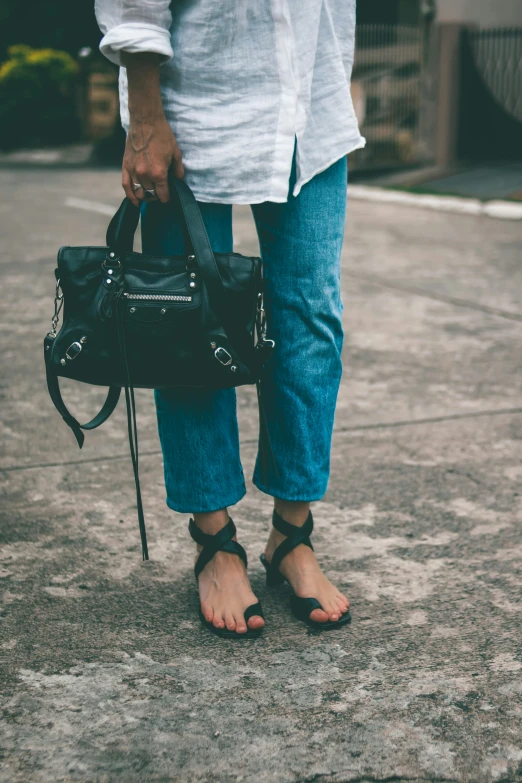 woman's feet with her handbag on the sidewalk