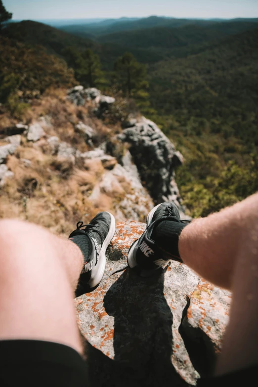 feet with sneakers on are sitting on a rock