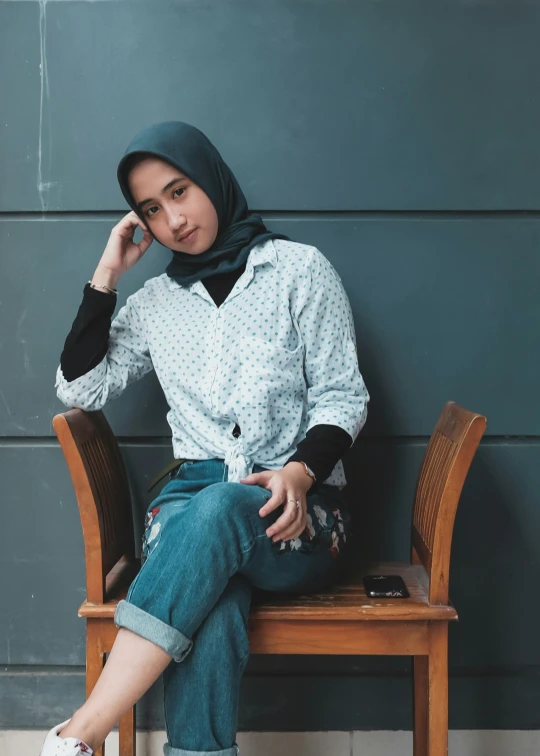 a woman in jeans and shirt sitting on a bench