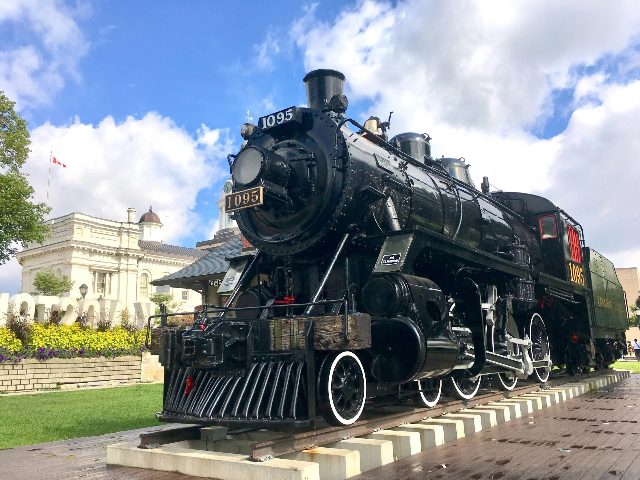 an old black locomotive parked at the side of a building