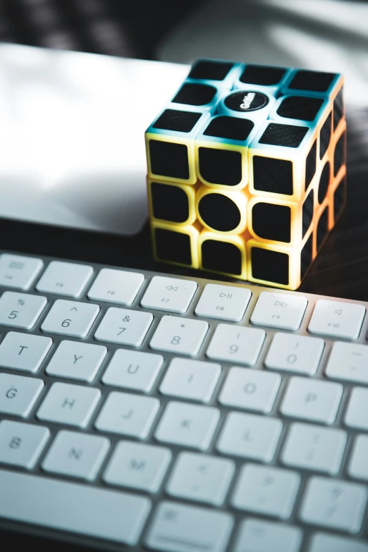 a small plastic rubik cube sitting next to a keyboard