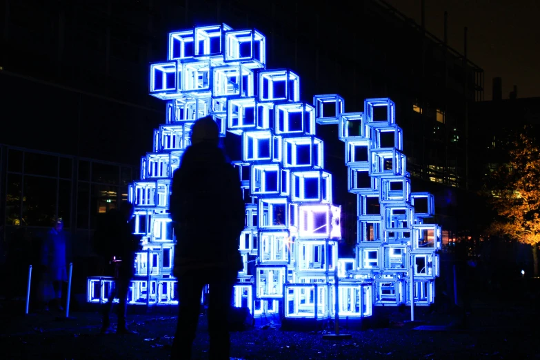 a person standing next to a sculpture made out of blocks