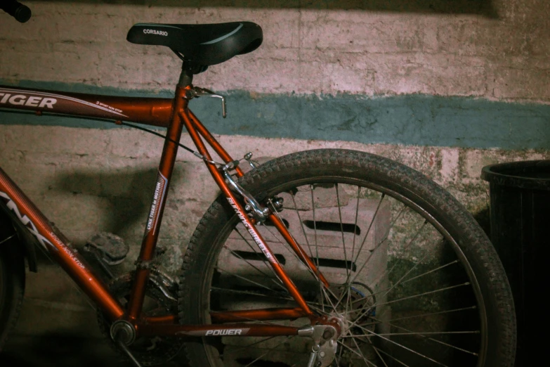 an orange bike sits against a brick wall