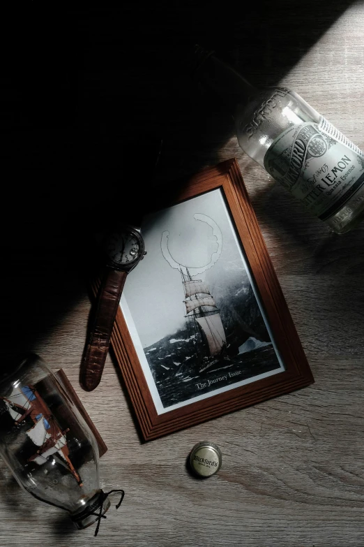 an empty vase, picture frame and a small key are on the floor next to a bottle