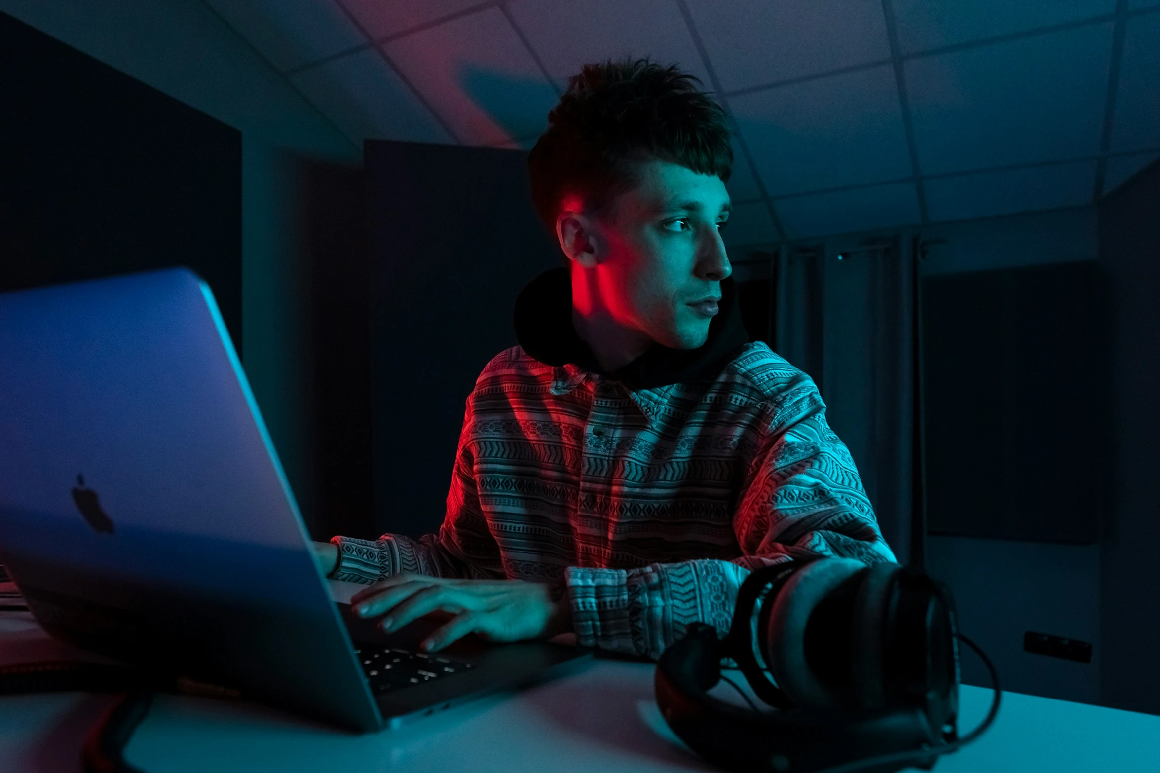 a young man sits in front of a laptop computer at night