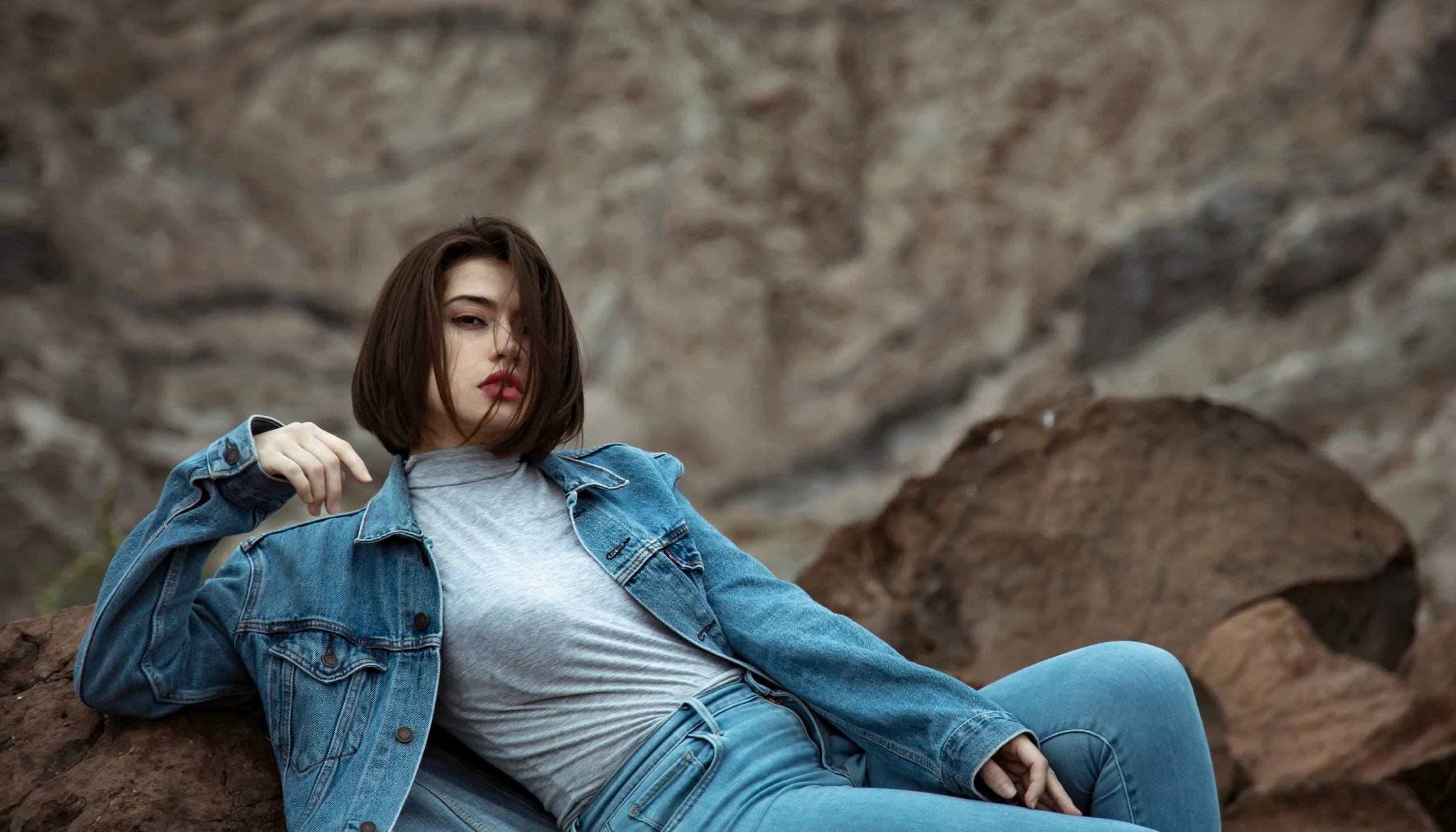 a young woman with dark hair sitting on rocks