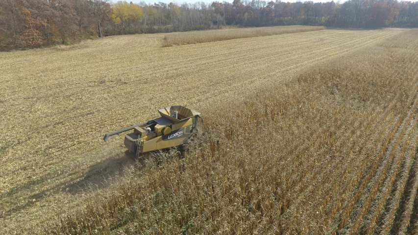 a yellow combine in a field being used by someone