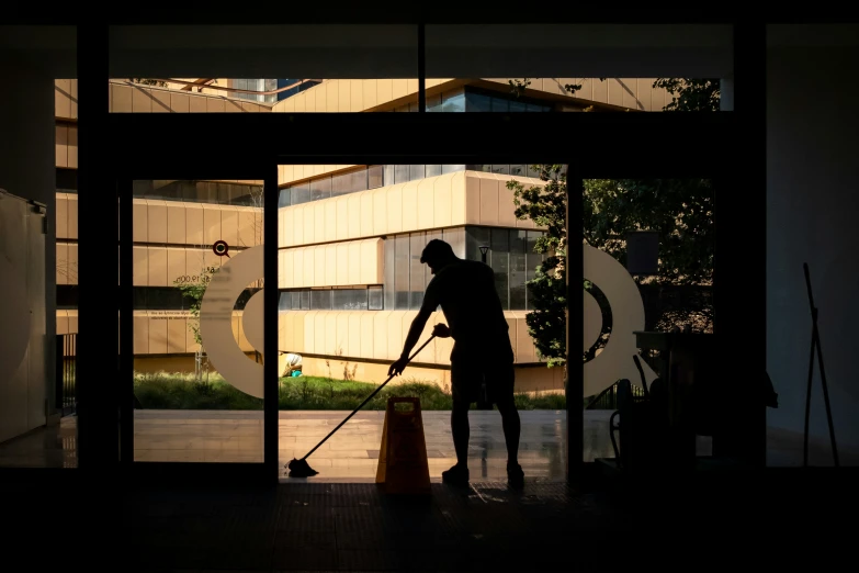 a silhouette of a man using an ironing board to clean a building