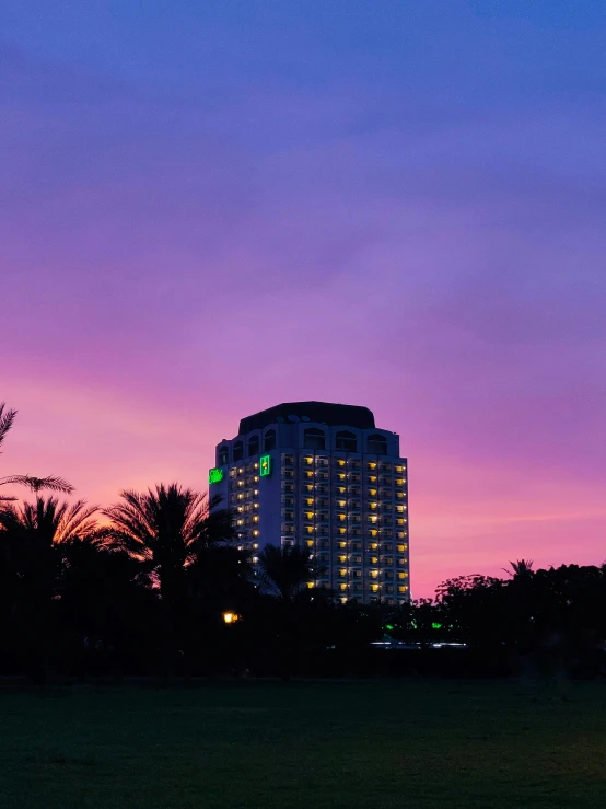 a tall building next to a forest during twilight